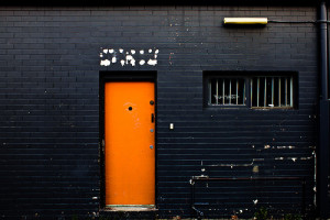 black brick wall with a steel orange door